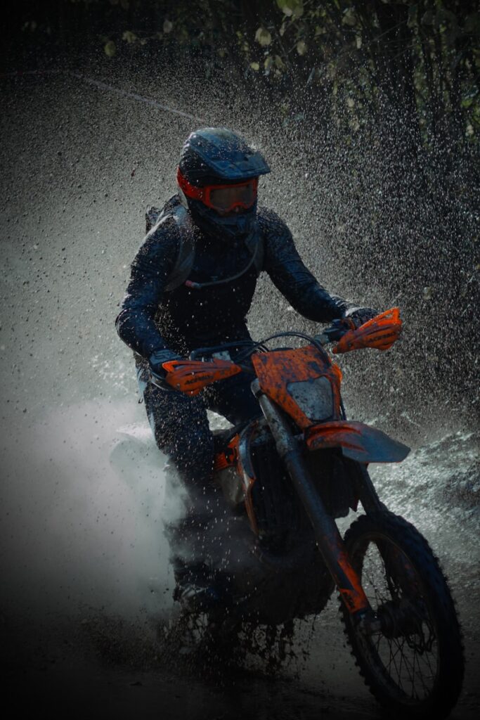 a man riding a dirt bike through a puddle of water